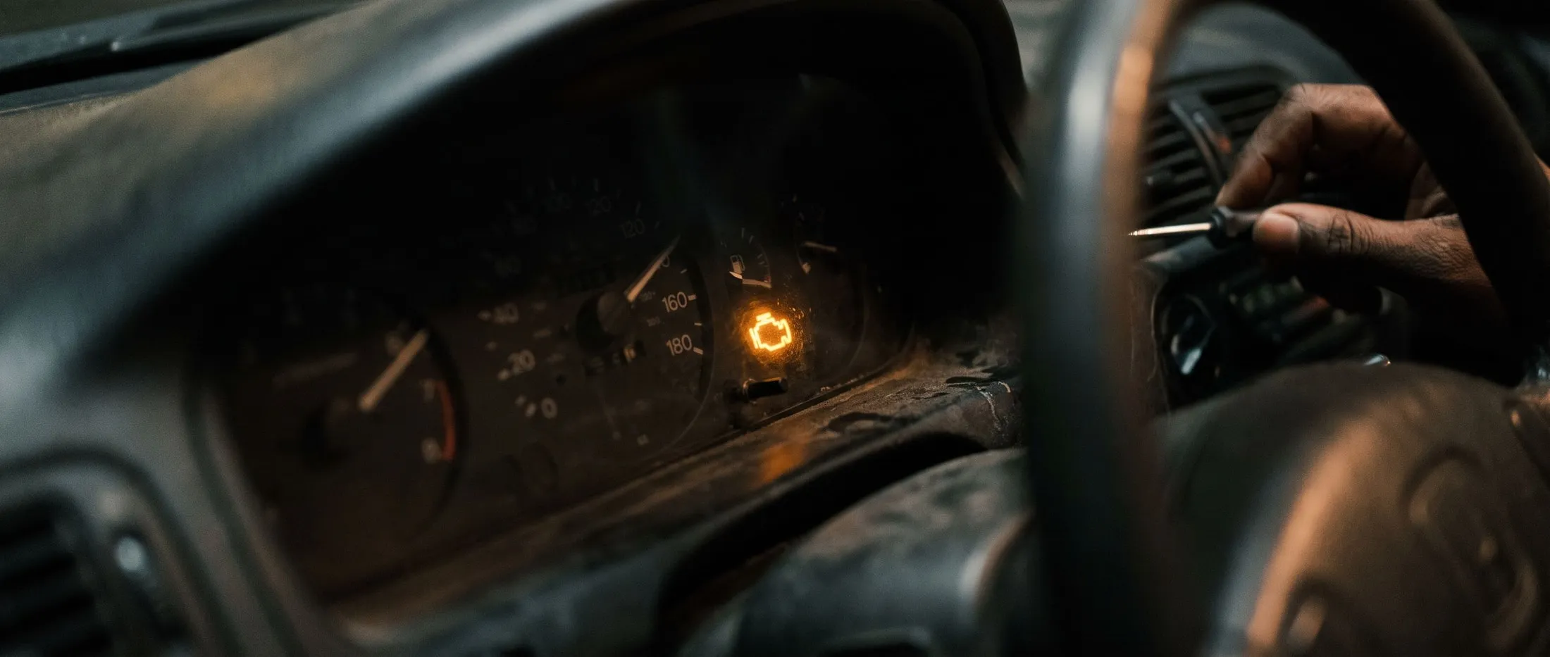 A lit amber check engine warning light on a car dashboard