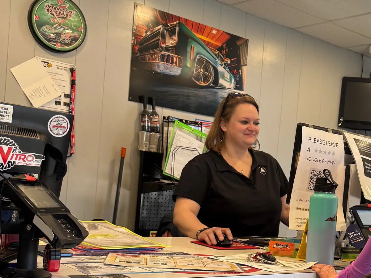 A member of staff behind the front counter at Lloyd's Tire & Auto, with the day's paperwork spread across it
