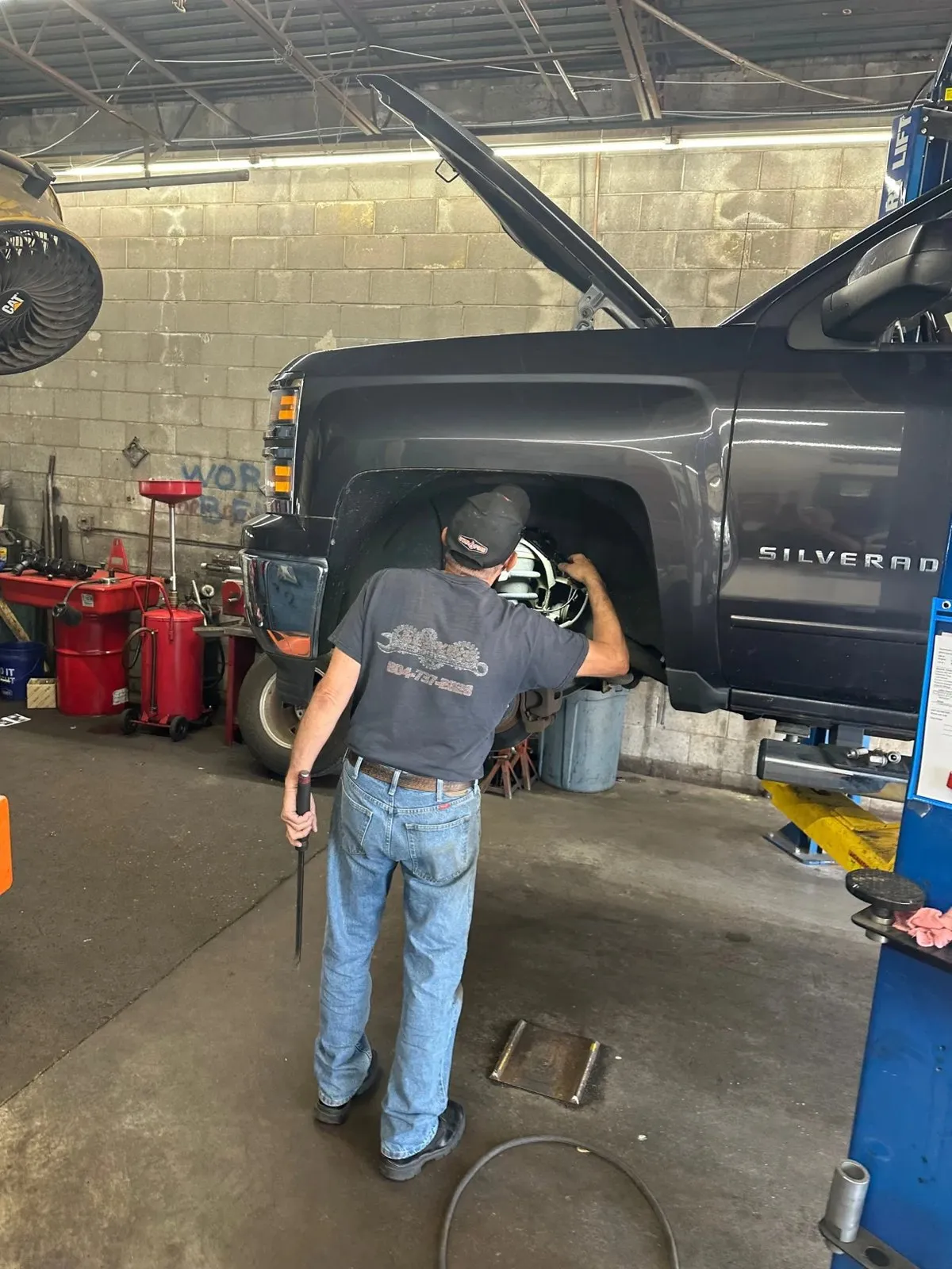 A Lloyd’s technician working on the front hub of a Chevrolet Silverado with the wheel removed